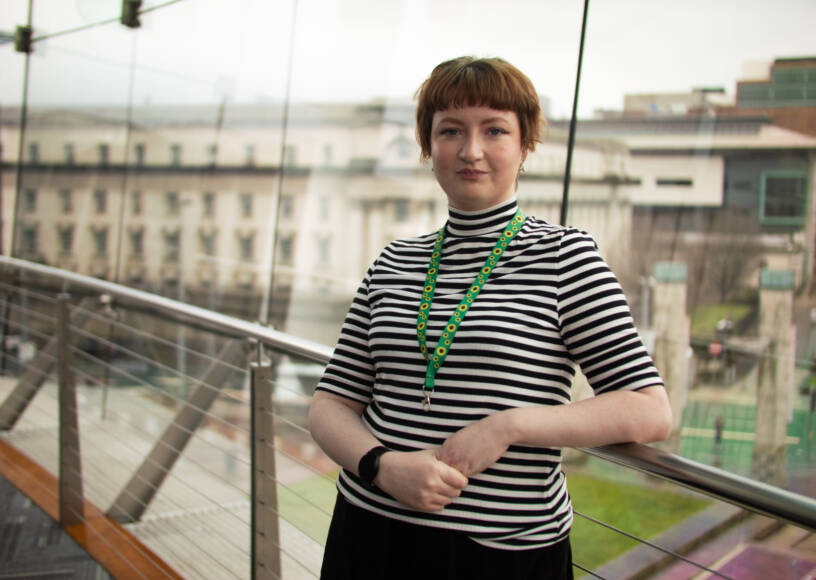 Woman smiles and poses in front of a large window