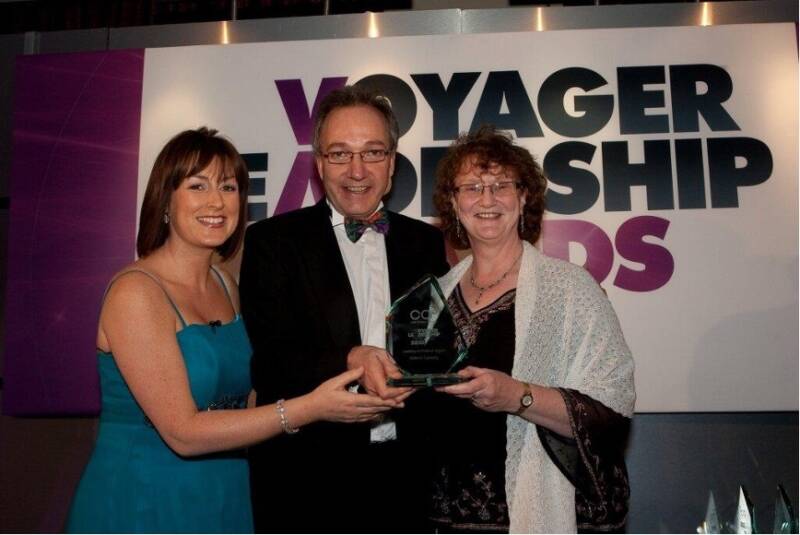 Several people smile and pose with an award