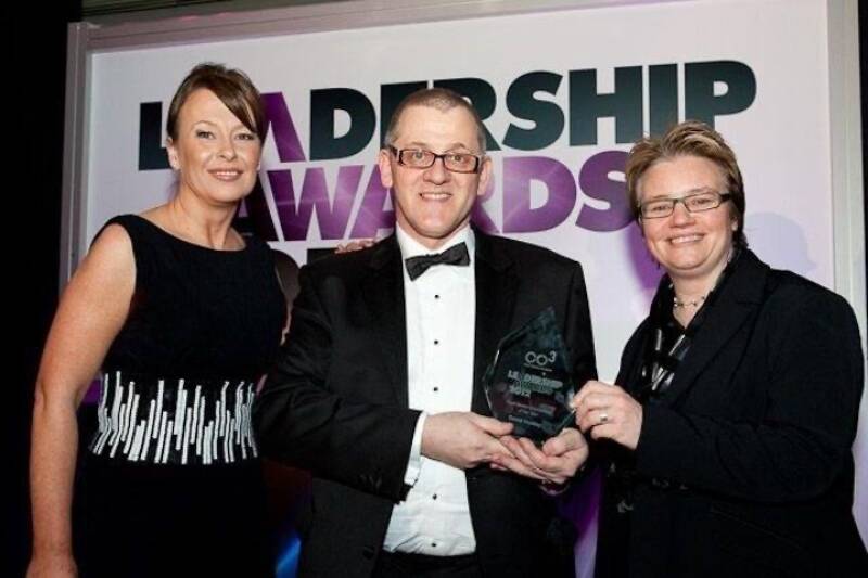 Several people smiling and posing with an award