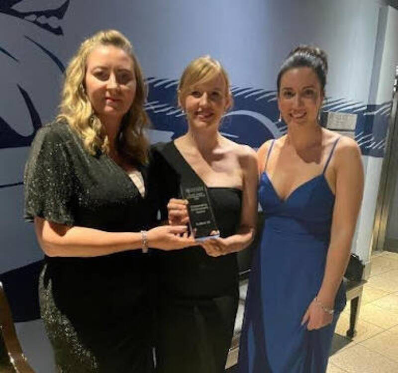 Several women smile and pose together with an award