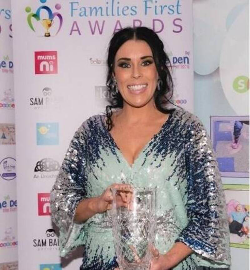Woman smiles and poses with a families first award
