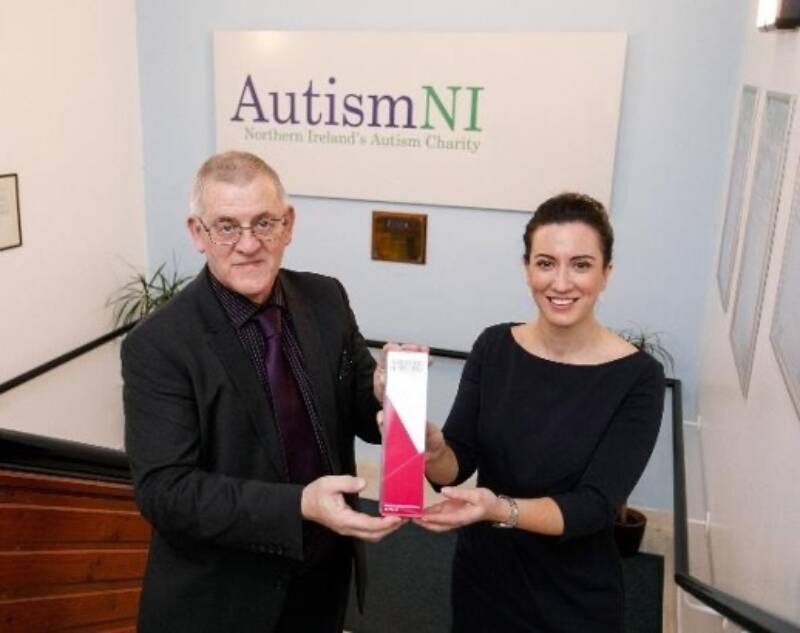 Two people smile and pose together with an award