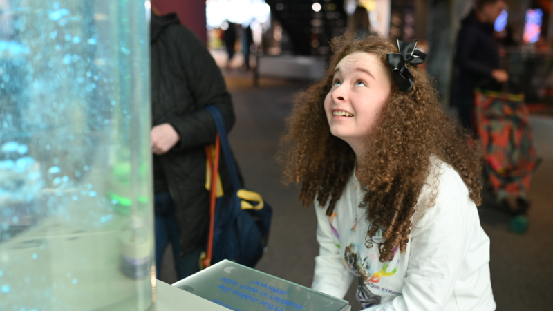 A young girl smiling and using an interactive bubbles display