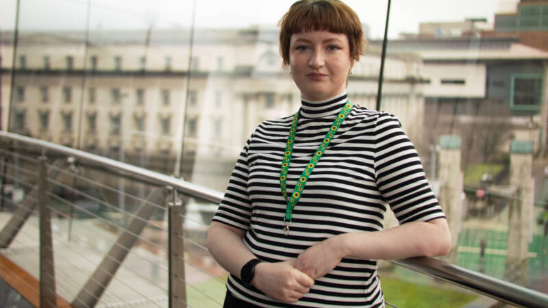 Woman smiles and poses in front of a large window