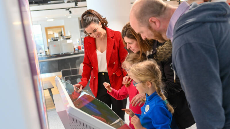 Several adults and a child looking at an interactive screen