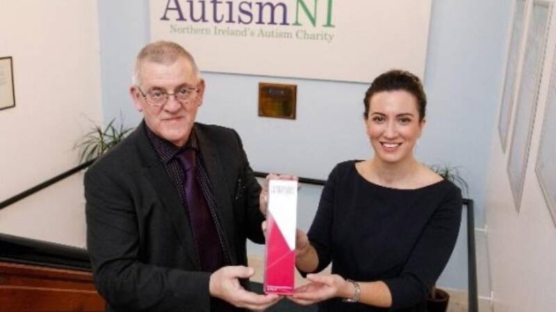 Two people smile and pose together with an award