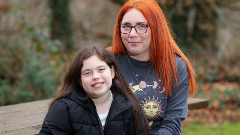 Mother and daughter smile together while sitting outside at a picnic bench