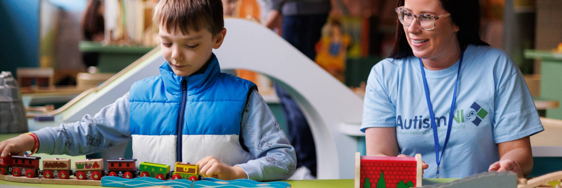 Woman and child playing with wooden trains together