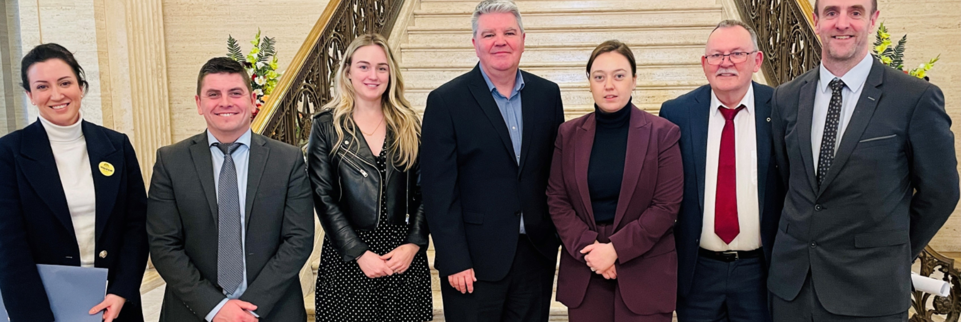 A group of people smiling and posing together in front of a staircase