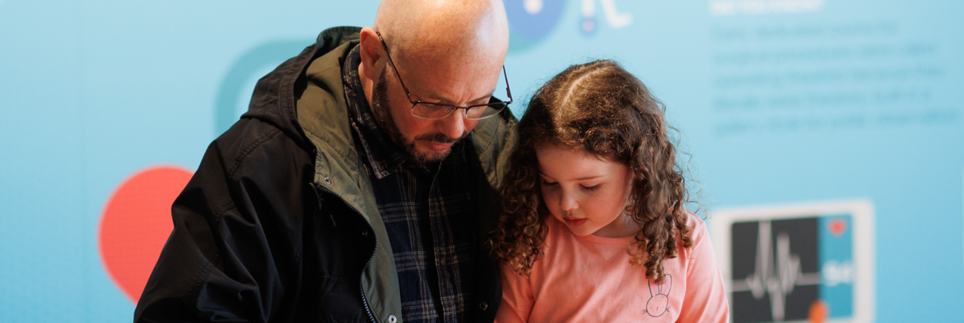 A father and daughter looking downwards together