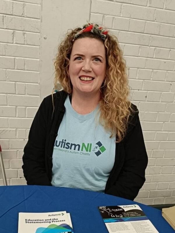 A woman smiling and wearing an Autism NI T-shirt