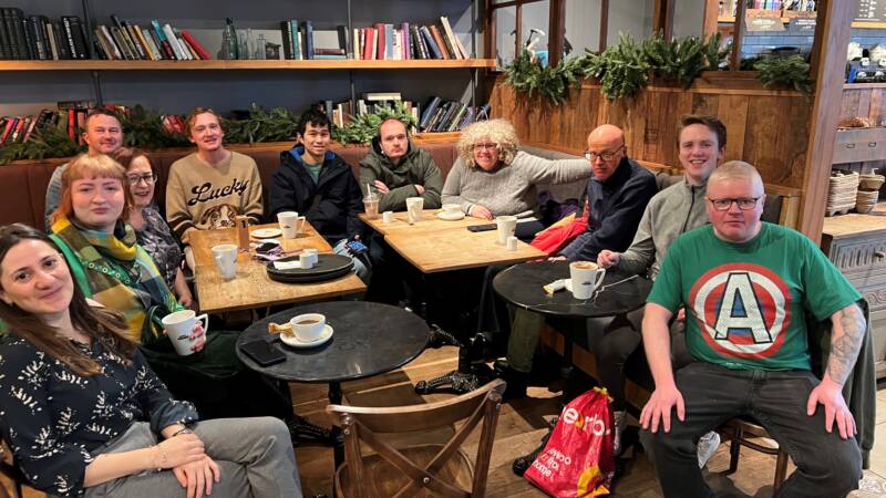 A group of people smile and pose sitting together in a café