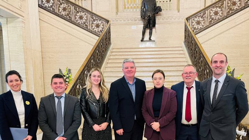 A group of people smiling and posing together in front of a staircase