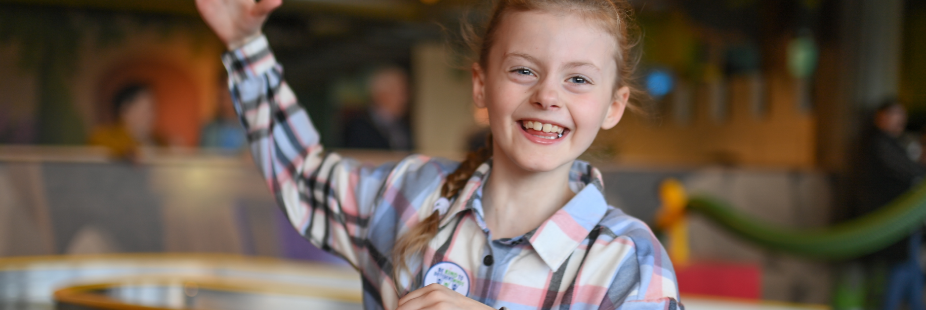 A young girl smiling and waving at the camera
