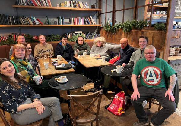 A group of people smile and pose sitting together in a café
